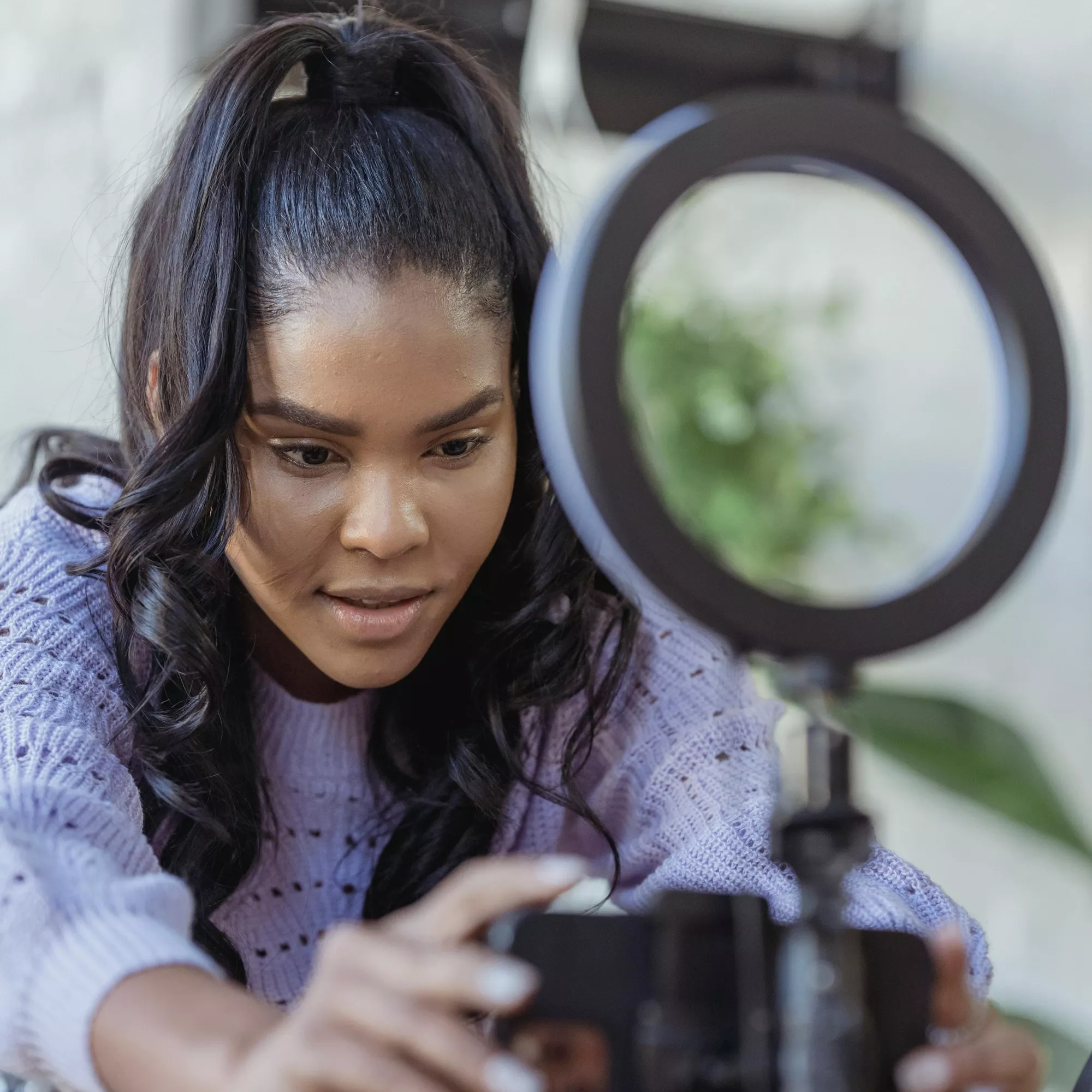 Woman adjusts a smartphone mounted on a tripod