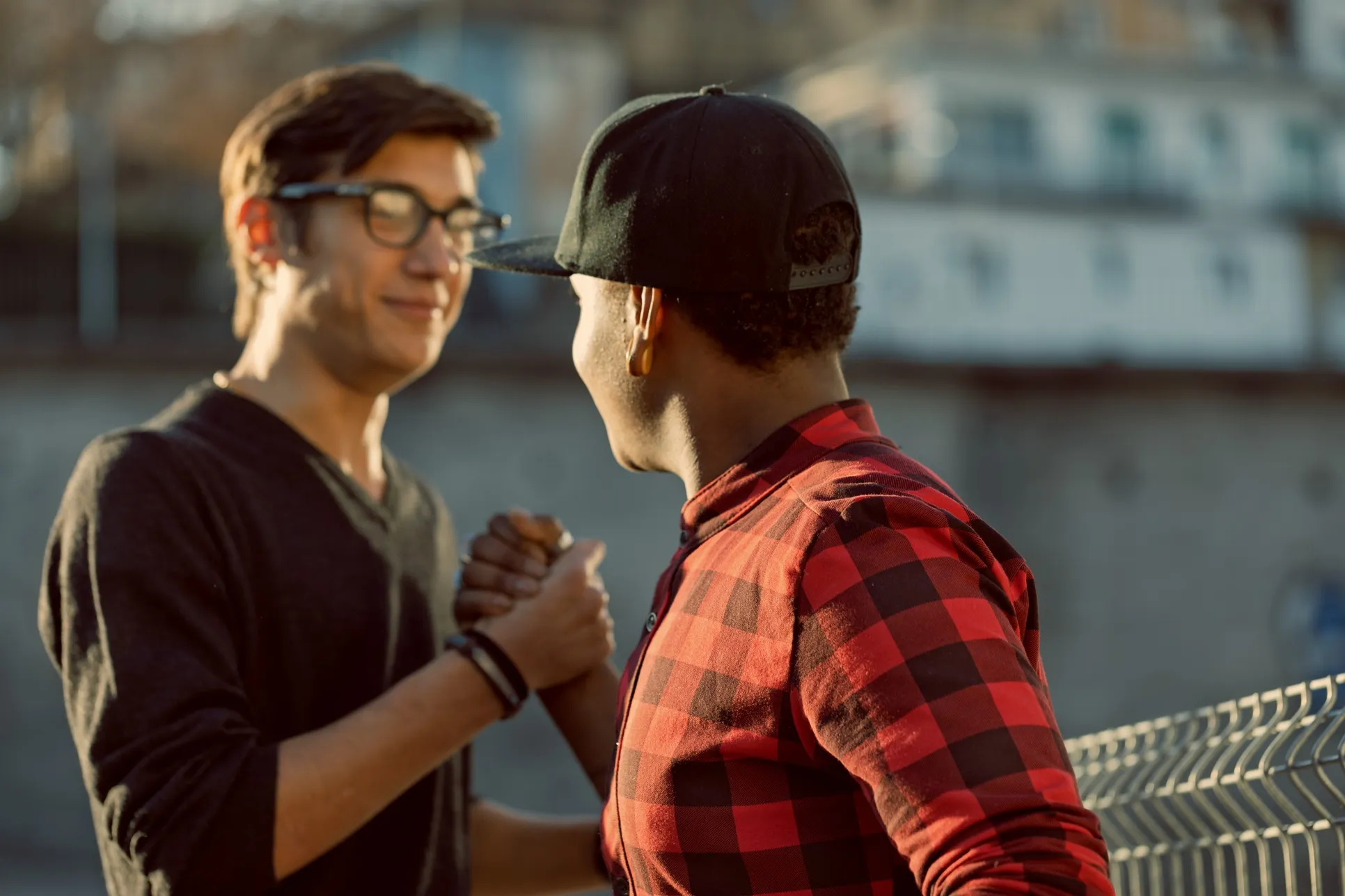 Two young men smile at one another as they shake hands