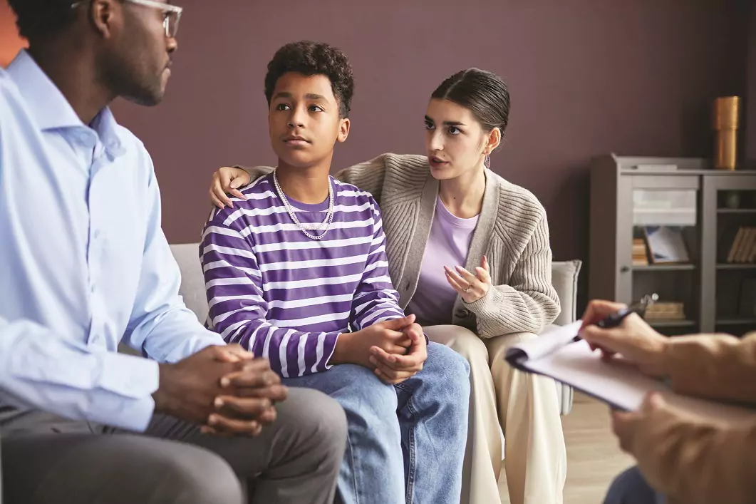 Counselor talks with teen boy and his mom and dad