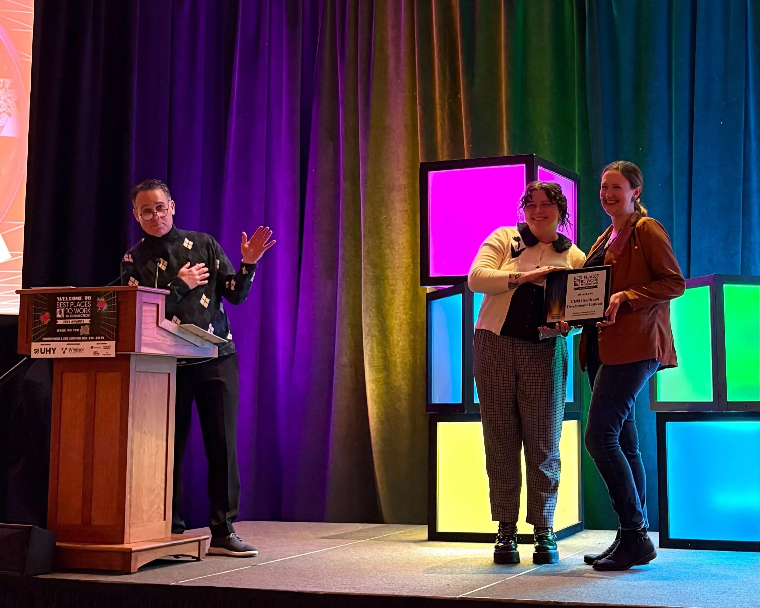 2 CHDI staff accept the 2026 Best Place to Work in CT Award on stage at awards dinner