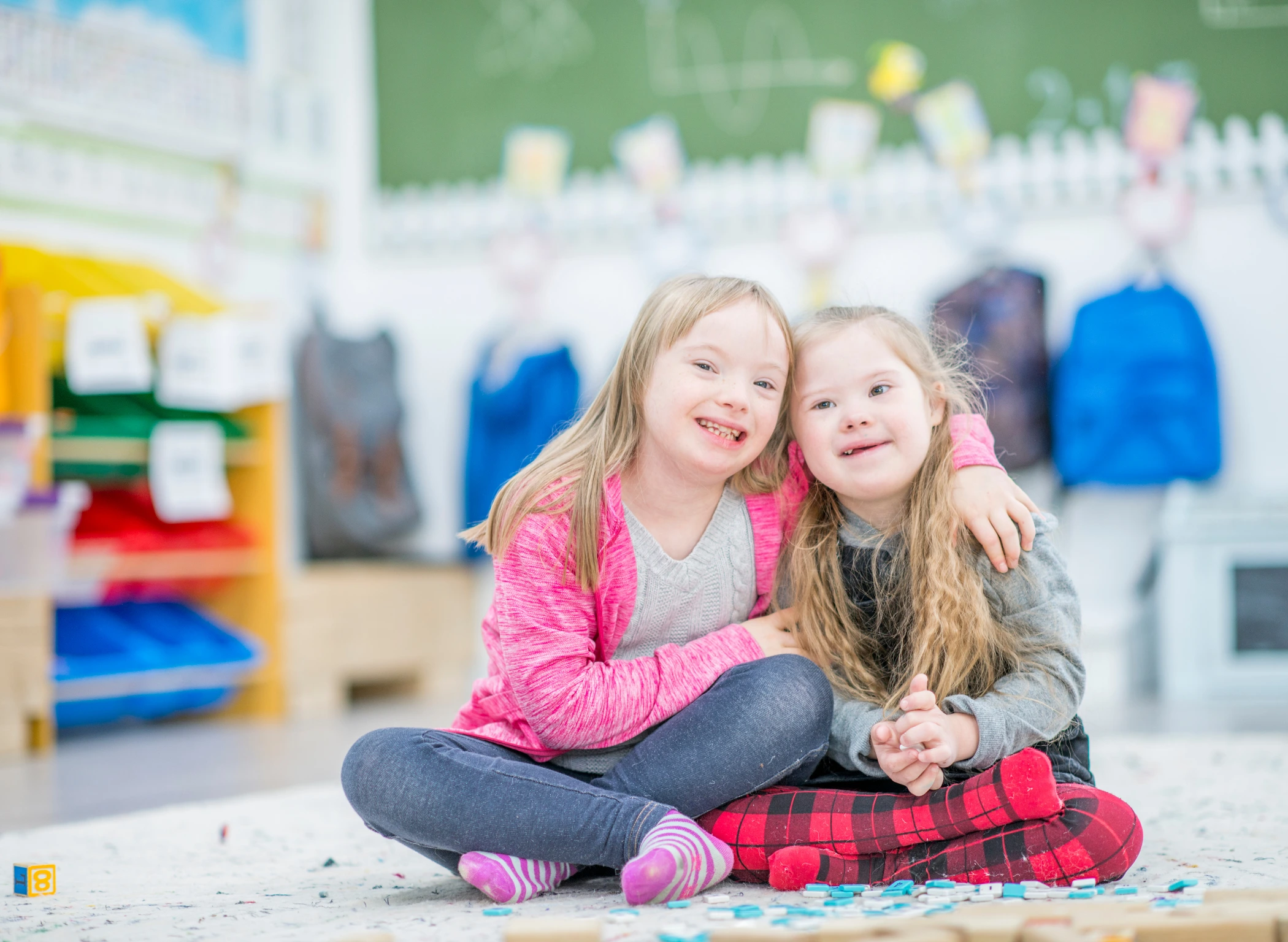 Two young girls with Down syndrome sit together at school