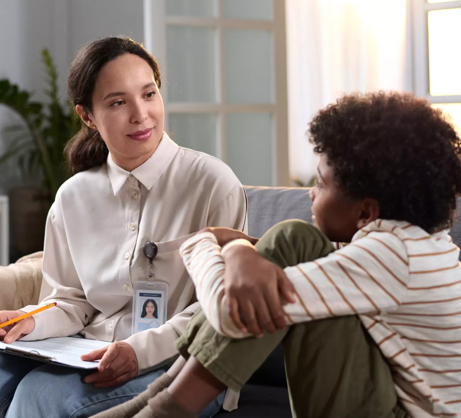 Caseworker kindly talks with preteen boy on couch